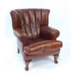 A tan leather wing armchair, with loose cushion seat, raised on mahogany cabriole legs, 105.5cm