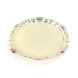 A Victorian silver card salver, of circular form with a pie crust rim, raised on three leaf scroll