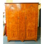 An early 20thC walnut and mahogany compactum wardrobe, the outswept pediment over two doors,