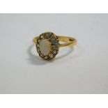 An 18ct gold and opal ring, set in a surround of clear brilliant cut stones, possibly white