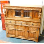 An Elizabethan style oak court cupboard, with carved S scroll top frieze, raised on leaf carved