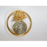 A 9ct two colour gold Northumberland Fusilliers brooch, of circular form, decorated with the