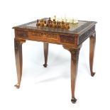 An Indonesian hardwood square games table, with brass inset chequer board top, having scroll foliate