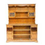 An Old Charm style oak dresser, the outswept pediment over a two shelf plate rack, with glazed