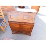 An oak bureau, the panelled fall front opening to reveal a single drawer and recesses, over a pair