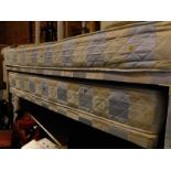 A single bed frame and mattress, with under storage for a guest mattress on a solid base with