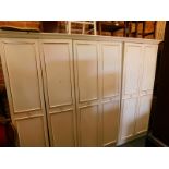 A white gilt trimmed MDF three section wardrobe, the outswept pediment over the six drawers