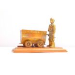 A Vale Metal Spinners Ltd brass sculpture, cast as a miner with a wagon of coal, raised on a