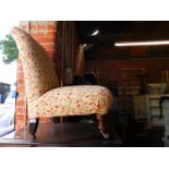 A Victorian nursing chair, upholstered in a modern foliate fabric, raised on turned front legs,