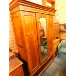 An Edwardian mahogany and satinwood cross banded double wardrobe, the outswept pediment over a