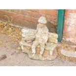 A reconstituted stone garden ornament, of a man on a bench.