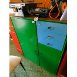 A Meredew green and blue painted teak cupboard, with a single door flanked by three drawers, above a