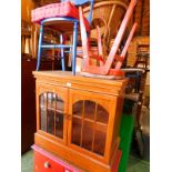 A yew wood laminate cabinet, the deeply moulded pediment over two glazed doors, raised on a plinth