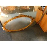 A gilt metal framed oval wall mirror, with bust and flower surmount, 66cm H, 39cm W., together
