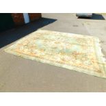 A Chinese wool rug, decorated with an oval central medallion, within a border of scrolling flowers