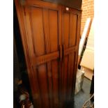 An oak Elizabethan style hall cupboard, with two doors opening to reveal a shelf above a hanging