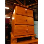 A pine bedside chest of three drawers, raised on turned feet, 61cm H, 45cm W, 43cm D.