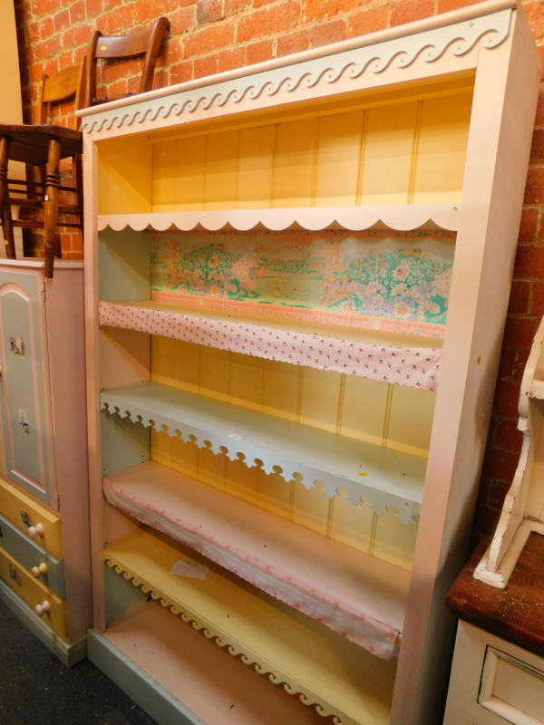 A pine bookcase, painted in pink, blue and yellow, the outswept pediment over five shelves with