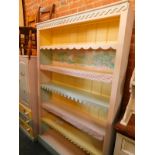 A pine bookcase, painted in pink, blue and yellow, the outswept pediment over five shelves with
