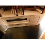 A grey painted wood television stand, with a drop down door and drawer, flanked by a deep cupboard