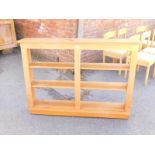 A set of pine shelves, three shelves with channelled supports, raised on a plinth base, 97cm H,