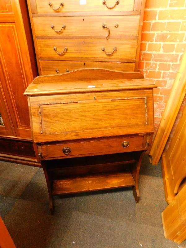 A mid 20thC student's oak bureau, the fall flap opening to reveal five recesses, over a frieze