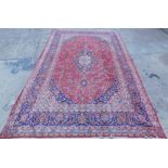 A large Persian carpet, of rectangular form, set with a geometric floral pattern, with an outer