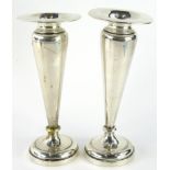A pair of Edwardian silver specimen vases, each with compressed rims, shouldered tapering stems