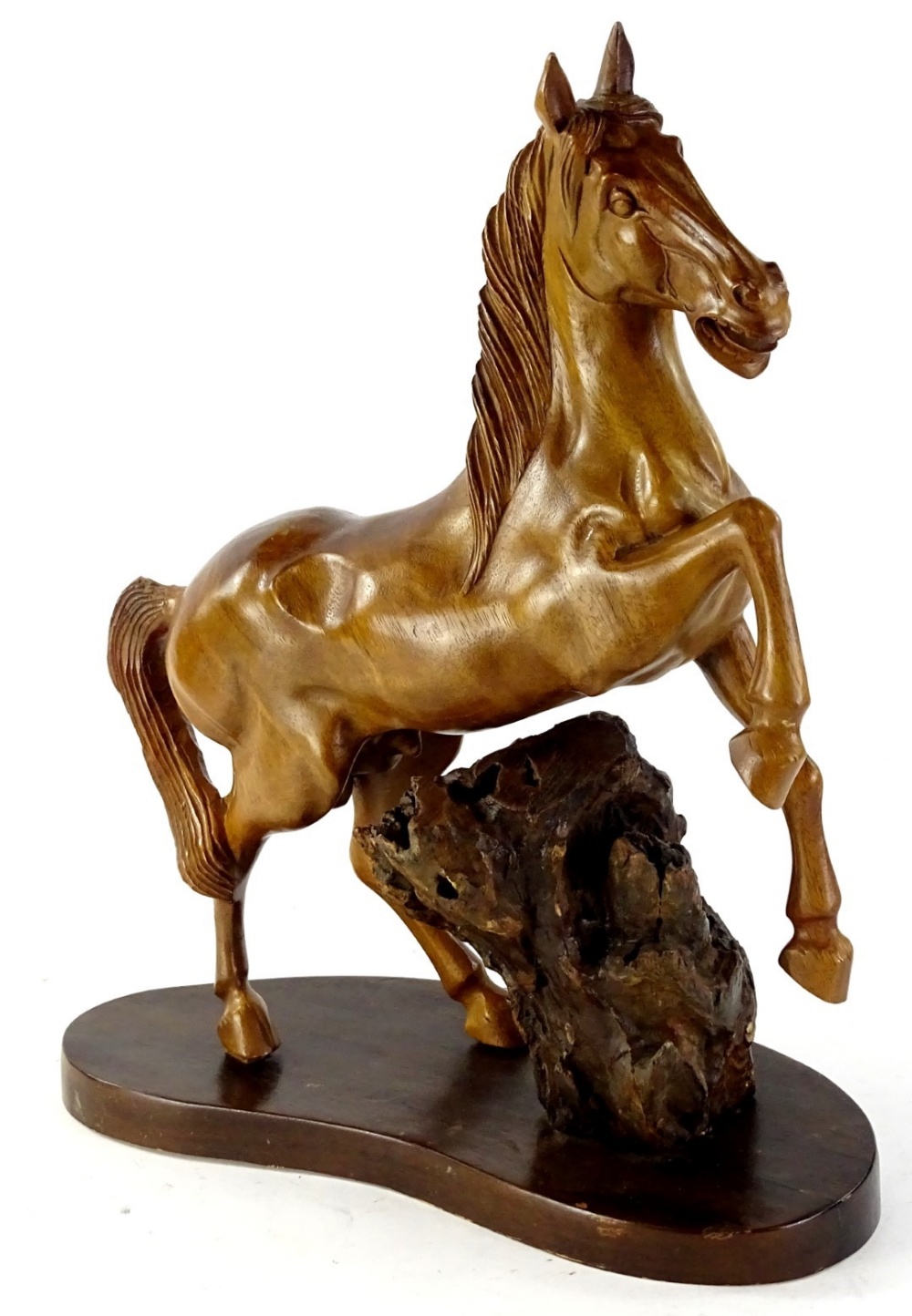 A 20thC heavily carved treen figure of a horse, with front leg raised, 40cm H, on a naturalistic