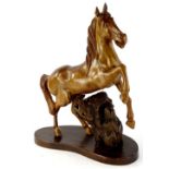 A 20thC heavily carved treen figure of a horse, with front leg raised, 40cm H, on a naturalistic