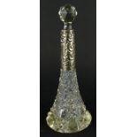 A late 19thC cut glass perfume bottle, with white metal repousse decorated collar, orb stopper and
