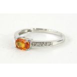 A 9ct gold dress ring, claw set with orange stone, flanked by small white stones to each shoulder,