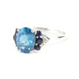 A 9ct gold dress ring, claw set with an oval blue stone, flanked by dark blue and white stones to