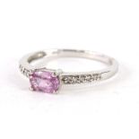 A 9ct white gold dress ring, claw set with a pink stone, flanked by white stones to each shoulder,