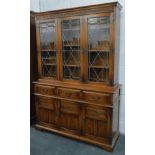 A Priory style oak display cabinet, the fixed moulded cornice raised above a carved frieze, with