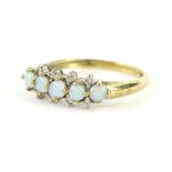 A 9ct gold dress ring, claw set with five opals and set with small white stones, on a part pierced