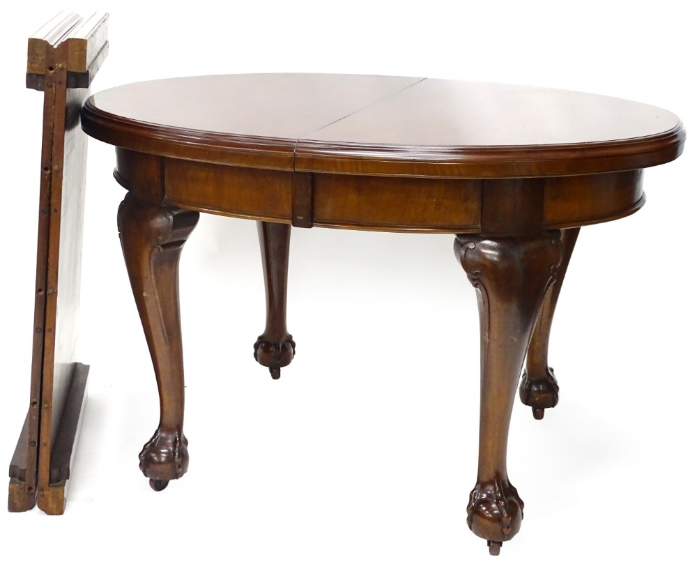 An Edwardian mahogany extending dining table, the oval top with a moulded edge on cabriole legs with