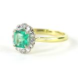 An 18ct gold diamond and emerald dress ring, the claw set central emerald surrounded by a floral