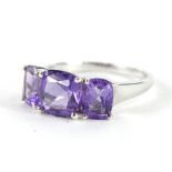 A 9ct white gold dress ring, claw set with three amethyst coloured stones to the part pierced shank,