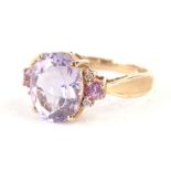 A dress ring, claw set with oval amethyst coloured stone, flanked by white and pink stones to each