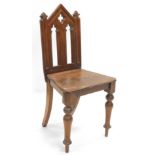 A late 19thC Gothic design oak hall chair, with pierced mitre back, canted seat and carved