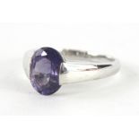 A 9ct gold solitaire dress ring, set with an oval purple stone, on a shaped Deco style shank, size