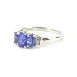 An 18ct white gold dress ring, claw set with three graduated bluey/purple stones, possibly