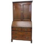 A George III oak bureau cabinet, the top with a moulded cornice above two panel doors, enclosing
