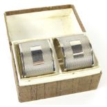 A cased pair of George VI silver napkin rings, each of cylindrical form, partially engine turned,