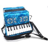 A child's piano accordion in blue, 29cm wide, in outer packaging.