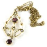 An early 20thC drop pendant of pear shaped form, claw set with a lower garnet and set with a further