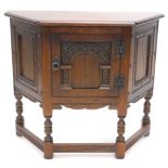 A Priory style oak side cabinet, the shaped top raised above a heavily carved door, with ring handle
