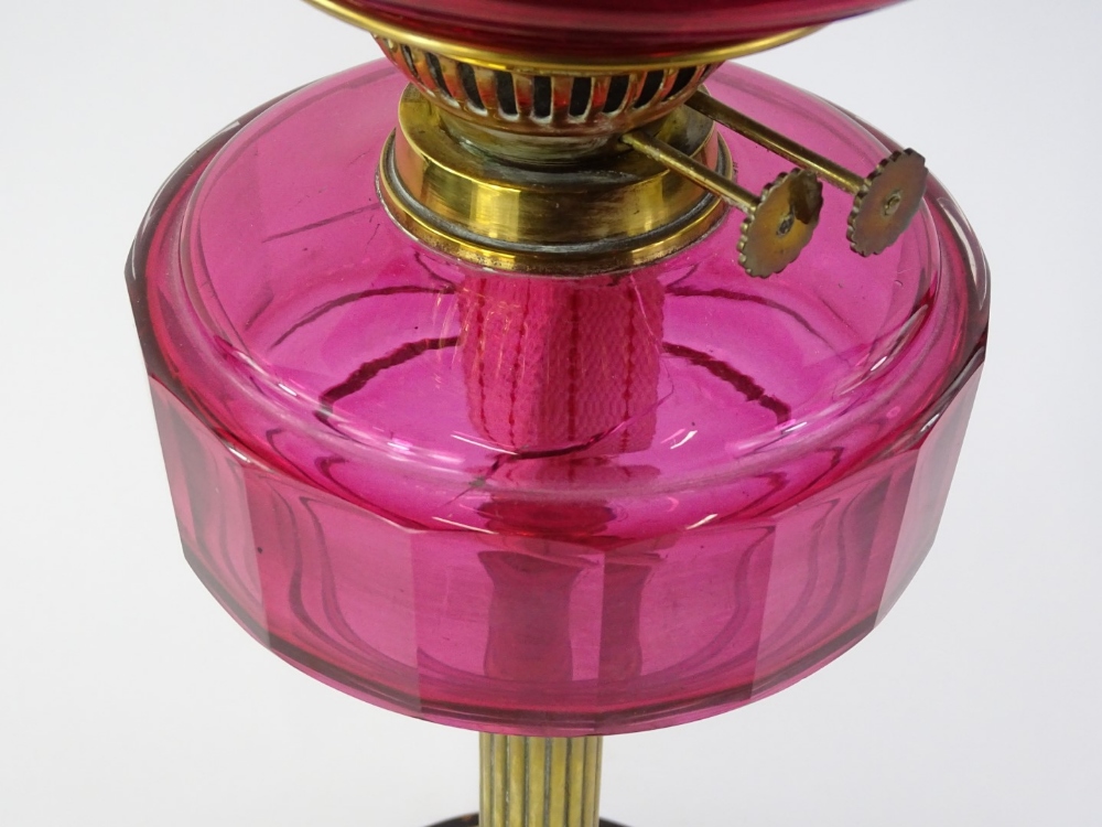 A Victorian brass oil lamp, with cranberry tinted shade and reservoir on reeded column with - Image 2 of 2