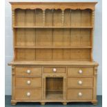 A reconstituted pine dresser, the upper section with a shaped frieze held by turned supports, with